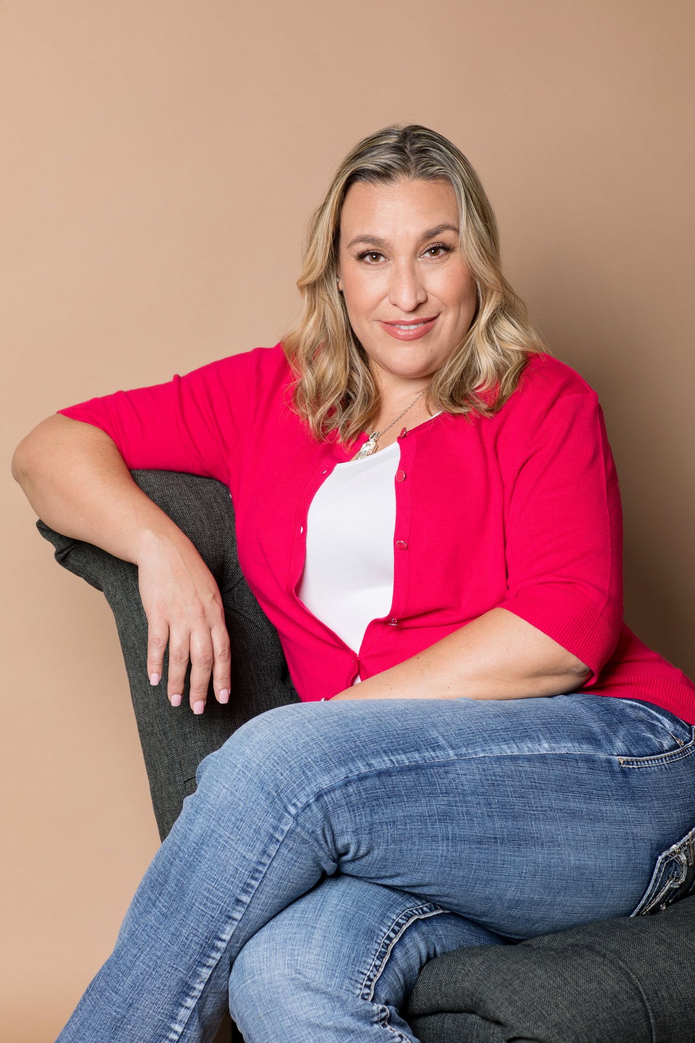 Jennifer Williams seated and smiling in a bright pink cardigan